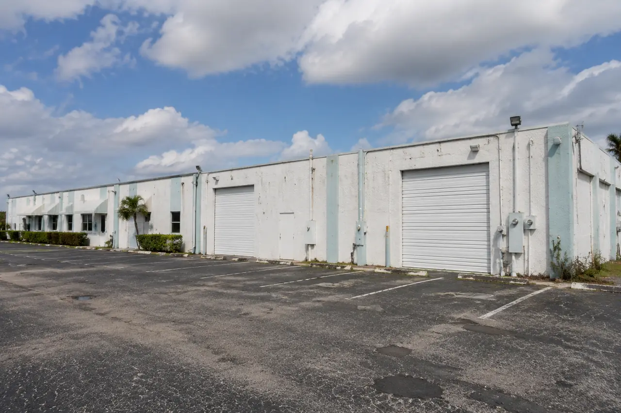 Older small-bay industrial property with faded striping and roll-up doors